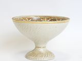 a white bowl with a gold rim on a white surface