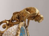 a close up of a gold and blue vase with a monkey on it