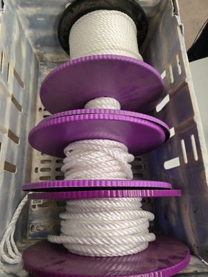 des bobines violettes et blanches dans un récipient en plastique contenant de la corde