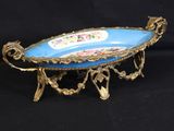 a blue and gold plate on a stand on a black background