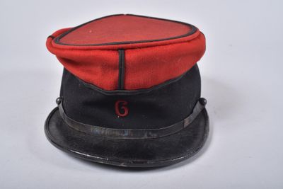 une image représentant un chapeau rouge et noir posé sur une table blanche