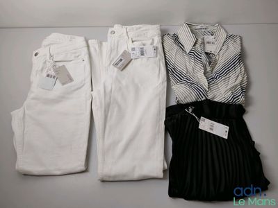 Deux paires de pantalons blancs et une chemise sont posés sur une étagère