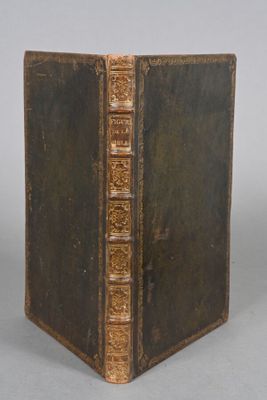 an old book sitting on top of a table next to a white wall