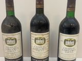 trois bouteilles de vin sont alignées sur une surface blanche