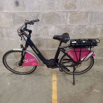 un vélo garé sur un parking, avec un sac rose à l'arrière