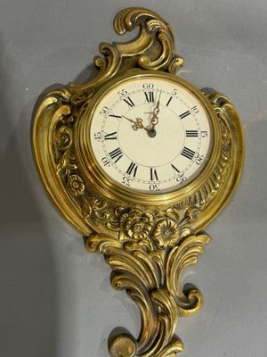 une horloge dorée avec des chiffres romains accrochée au mur