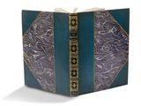 un livre bleu aux bords dorés, avec un motif décoratif sur la couverture