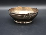 silver plated bowl on a black surface with a black background