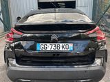 the rear end of a black car parked in front of a building