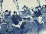 a blue and white plate with a picture of a group of people playing a game