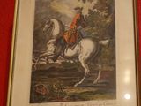 un tableau encadré représentant un homme à cheval, accroché à un mur rouge