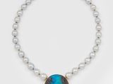 un gros plan sur un collier composé de perles et d'une pierre bleue