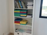 a white bookcase with many books on top of it