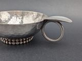 a silver bowl with a spoon in it on a table