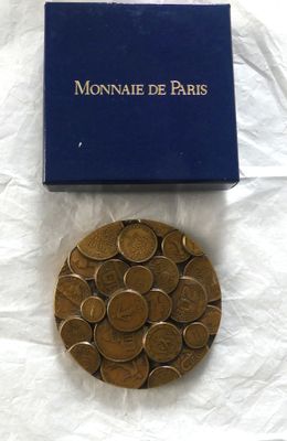 une boîte bleue remplie de pièces posée sur une surface blanche, à côté d'une boîte remplie de pièces