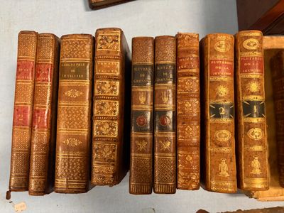 Plusieurs vieux livres sont alignés sur une étagère à côté d'une horloge