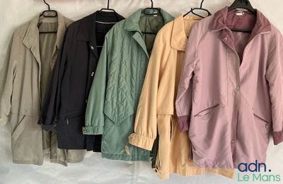 plusieurs vestes suspendues à un porte-manteau devant un mur blanc