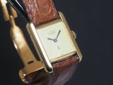 une montre-bracelet en or avec un bracelet en cuir marron
