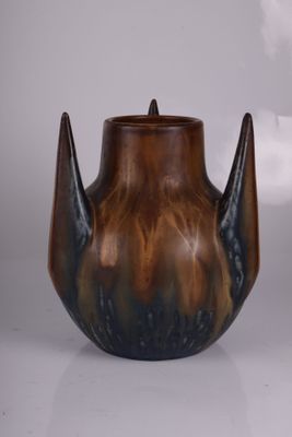 un vase marron et noir posé sur une table, sur fond blanc