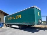 une semi-remorque verte garée devant un immeuble