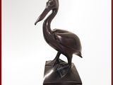 une statue en bronze représentant un pélican posé sur un socle