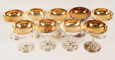 neuf verres à vin à bord doré posés sur une surface blanche