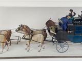 une maquette d'une calèche tirée par des chevaux avec des passagers à l'intérieur