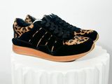 des baskets noires à imprimé léopard posées sur un socle blanc, sur fond blanc