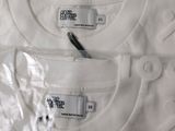 three white t - shirts with tags on them on a table