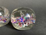 two clear glass balls filled with colorful confetti sprinkles
