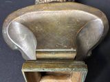 a bronze sculpture of a chair with a lion head on top of it