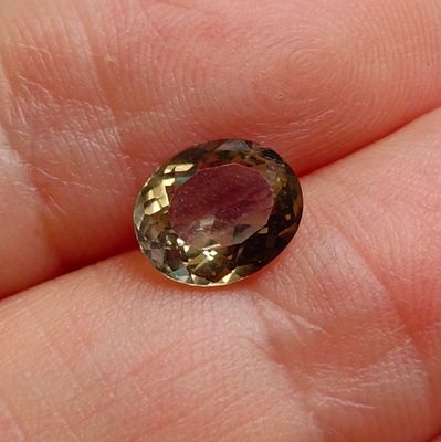 a close up of a person ' s hand holding a yellow and brown gemstone