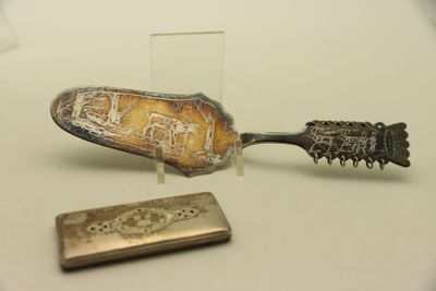 une cuillère en argent et un petit objet en métal posés sur une table