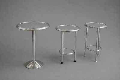 trois tables d'appoint en métal argenté sur fond gris