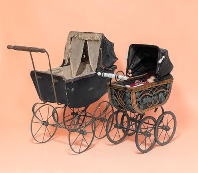 an old fashioned baby carriage with a baby in it on a pink background