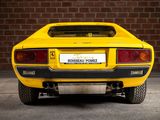 the rear end of a yellow sports car parked in front of a brick wall