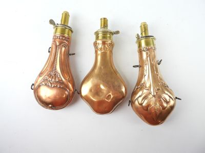 three antique copper bottle shaped ornaments on a white surface