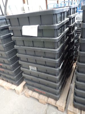 de nombreux bacs en plastique noir empilés sur une palette