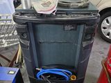une poubelle noire équipée d'un tuyau, dans un garage