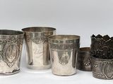 Plusieurs coupes et tasses en argent sont alignées sur une surface blanche