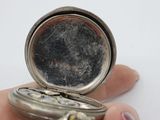 a person holding a silver pocket watch in their hand