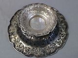 a silver plate with a bowl on it on a table