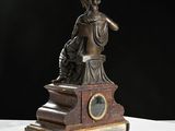 a bronze statue of a woman sitting on a pedestal