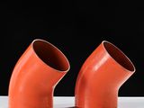 two orange pipe fittings on a white surface against a black background