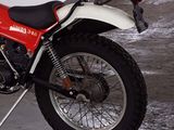 a red and white motorcycle parked next to a white wall