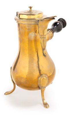 une cafetière ancienne en laiton posée sur un support, sur fond blanc