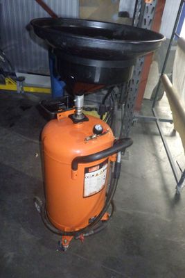 un réservoir orange surmonté d'une cuve noire, dans un garage