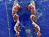 une paire de boucles d'oreilles en grenat et diamant posées sur une dalle de pierre bleue