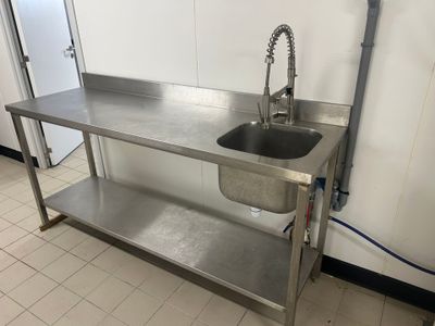 un évier en acier inoxydable et un plan de travail en acier inoxydable dans une cuisine professionnelle
