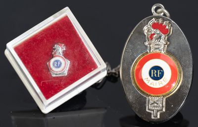 deux boutons de manchette argentés et rouges, accompagnés d'un coffret rouge et d'un insigne argenté et rouge